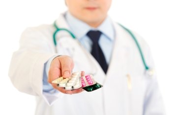 Doctors hand holding packs of pills isolated on white. Close-up.
