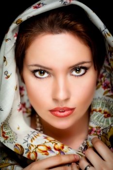 Portrait of beautiful girl  with old russian shawl on head on black background. Retouched
