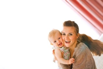 Portrait of happy young mother with her smiling baby at home
