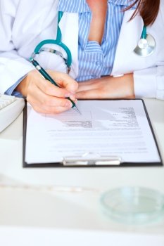 Close up on medical doctor woman sitting at table and working with document
