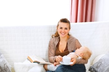 Young mom resting while baby sleep by having coffee and reading book

