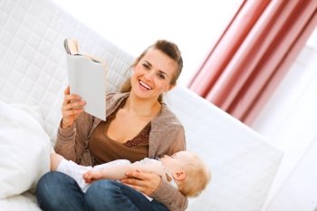 Smiling young mother resting while baby sleep by reading book at home
