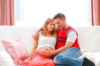 Happy young man holding his pregnant wifes belly
