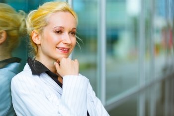 Pensive modern business woman with hand near face standing near office building 
