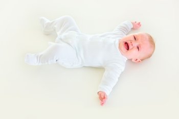 Crying four month old  baby girl laying on back
