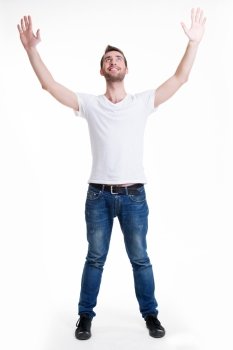 Young happy man in casuals with raised hands up - isolated on white.