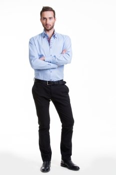 Portrait of serious man in blue shirt and black pants with crossed arms - isolated on white.
