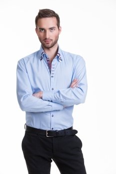 Portrait of serious man in blue shirt and black pants with crossed arms - isolated on white.
