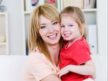 Portrait of happy smiling cheerful mother with daughter in embracing  -  indoors
