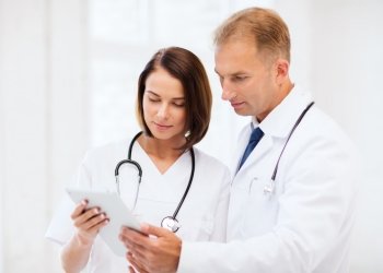healthcare and medical and technology concept - two doctors looking at tablet pc