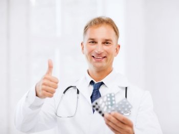 healthcare, medical and pharmacy concept - male doctor with packs of pills