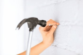 architecture and home renovation concept - architect hammering nail in wall
