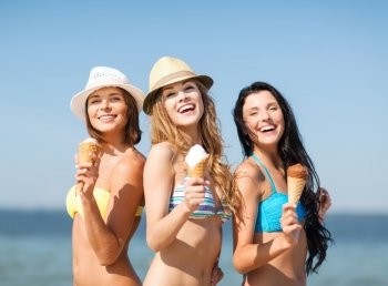 summer holidays and vacation - girls in bikinis eating ice cream on the beach