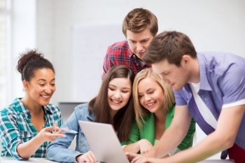education and internet concept - group of international students looking at laptop at school