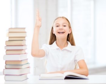 education and school concept - little student girl with books raising hand up at school