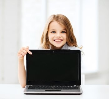 education, school, technology and internet concept - little student girl pointing at laptop pc at school