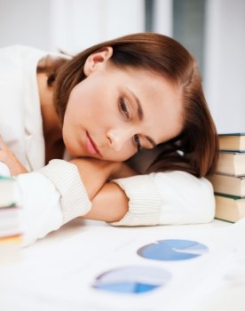 education and business concept - bored young woman with many books and graphs indoors