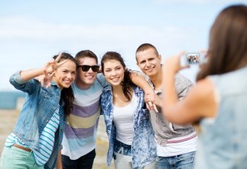 summer holidays and technology concept - group of teenagers taking photo outside