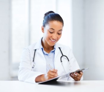 healthcare and medical concept - female doctor with stethoscope writing prescription