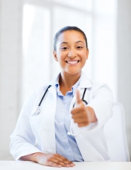 healthcare and medical concept - african doctor with stethoscope showing thumbs up