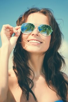 holidays and beach concept - beautiful woman in bikini and sunglasses