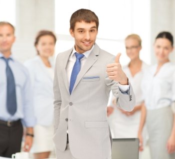 office, buisness, teamwork concept - friendly young smiling businessman with thumbs up
