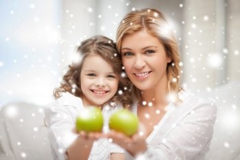 family, children, christmas, x-mas, love concept - mother and daughter holding green apples
