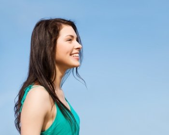 summer holidays and vacation - beautiful smiling girl over blue sky