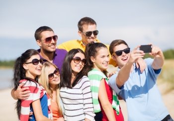 summer, holidays, vacation, happy people concept - group of friends taking picture with smartphone