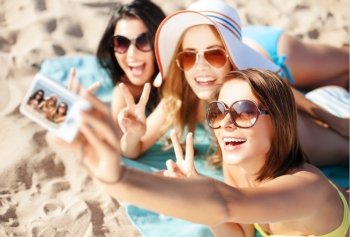 summer holidays, vacation and beach concept - girls taking self photo on the beach