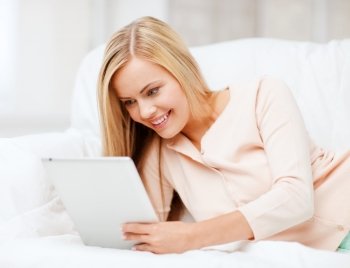 leisure and education concept - smiling woman lying on the couch with tablet pc
