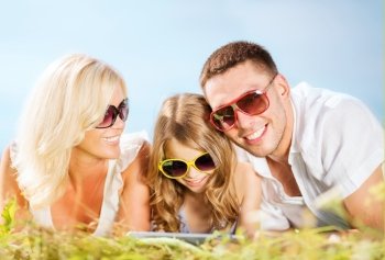 summer holidays, children and people concept - happy family with tablet pc, blue sky and green grass
