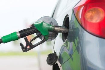 transportation and ownership concept - pumping gasoline fuel in car at gas station
