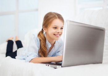 education, free time, technology and internet concept - little student girl with laptop pc at home
