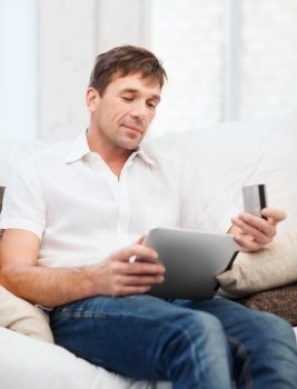 online or internet shopping concept - smiling man with tablet pc and credit card at home