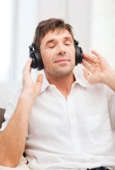 leisure and lifestyle concept - happy man with headphones listening to music at home