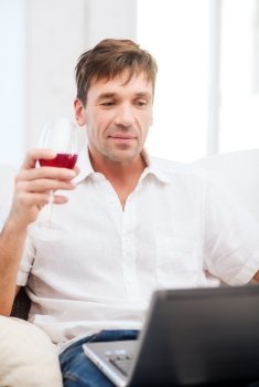 technology, business, leisure, drinks, retirement and lifestyle concept - happy man with laptop computer and glass of rose wine at home