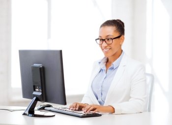business and internet concept - smiling african businesswoman with computer in office