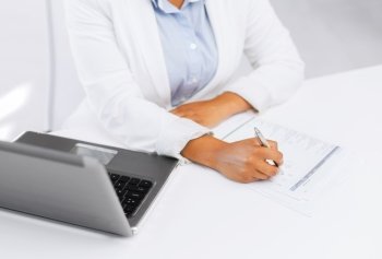 business, education and technology concept - businesswoman with laptop filling a form