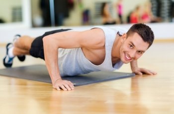 fitness, sport, training, gym and lifestyle concept - smiling man doing push-ups in the gym