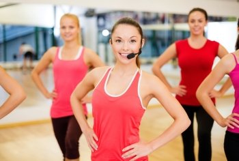 fitness, sport, training, gym and lifestyle concept - group of smiling people with trainer exercising in the gym