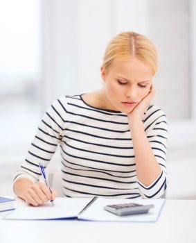 education, school and business concept - worried woman with notebook and calculator studying in college