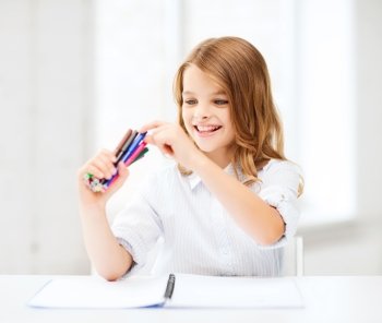 education, creation and school concept - smiling little student girl choosing colorful felt-tip pen at school