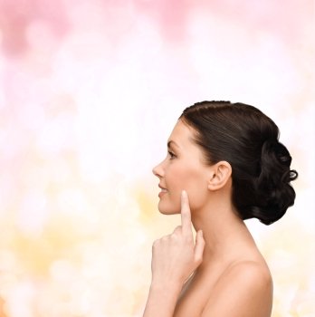 beauty, spa and health concept - smiling young woman pointing to her cheek