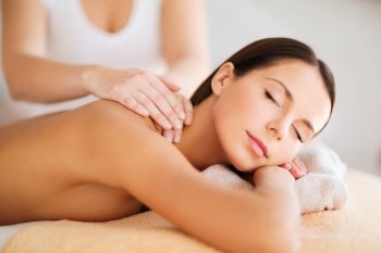 beauty, spa, resort and relaxation concept - beautiful woman in spa salon getting massage
