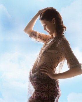 family, motherhood and pregnancy concept - silhouette backlight picture of pregnant beautiful woman