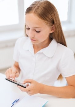 education, school, technology and internet concept - little student girl with notebook and smartphone at school