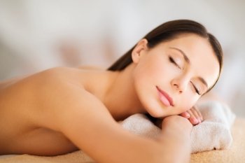 health and beauty, resort and relaxation concept - beautiful woman with closed eyes in spa salon lying on the massage desk