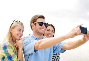summer, holidays, vacation and happiness concept - group of friends taking picture with smartphone