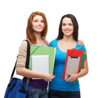 education, technology and people concept - two smiling students with bag, folders and tablet pc standing
